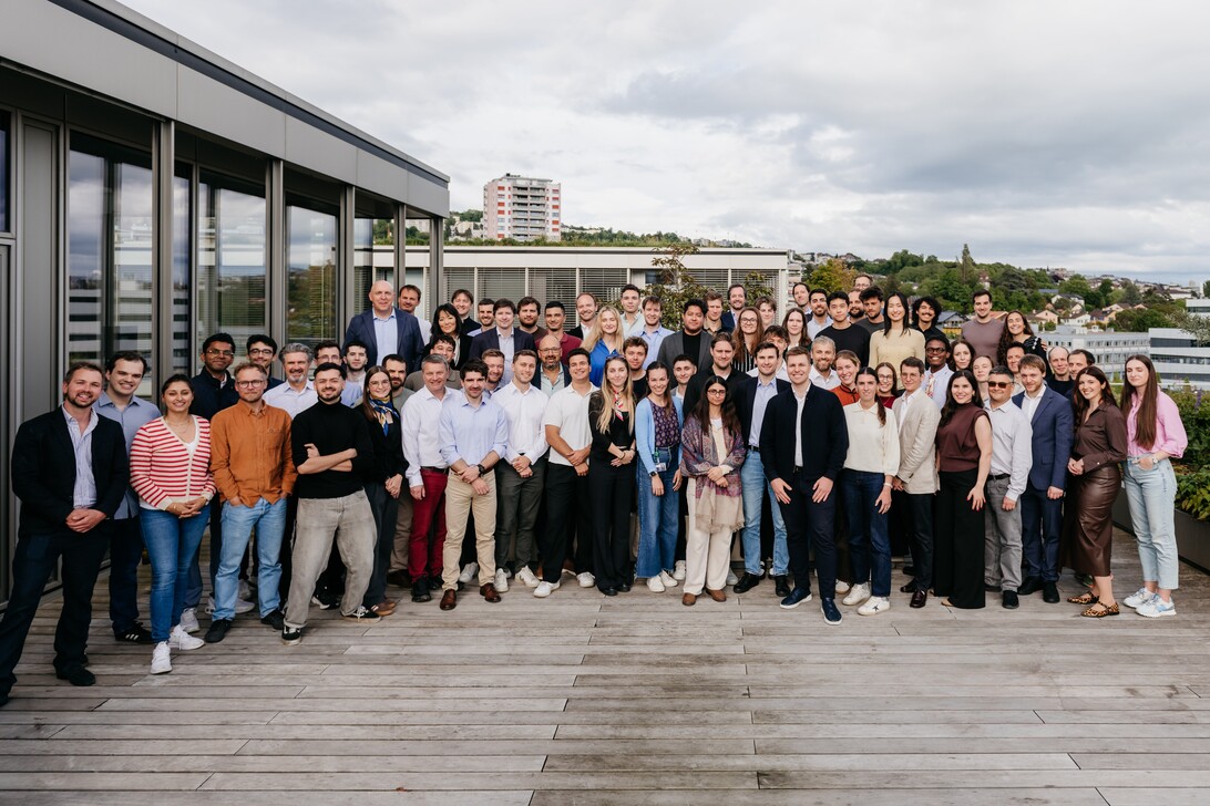 Visium - IP - EconomiaeInversion.com Large diverse group of professionals posing on a rooftop terrace with a city skyline in the background.