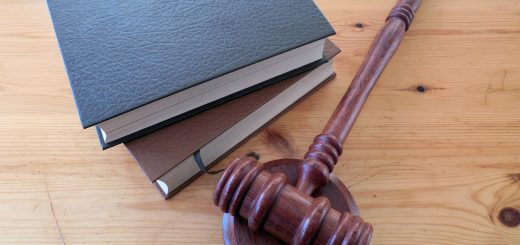 Gavel resting on a stack of three hardbound books on a wooden table, symbolizing law and justice.
