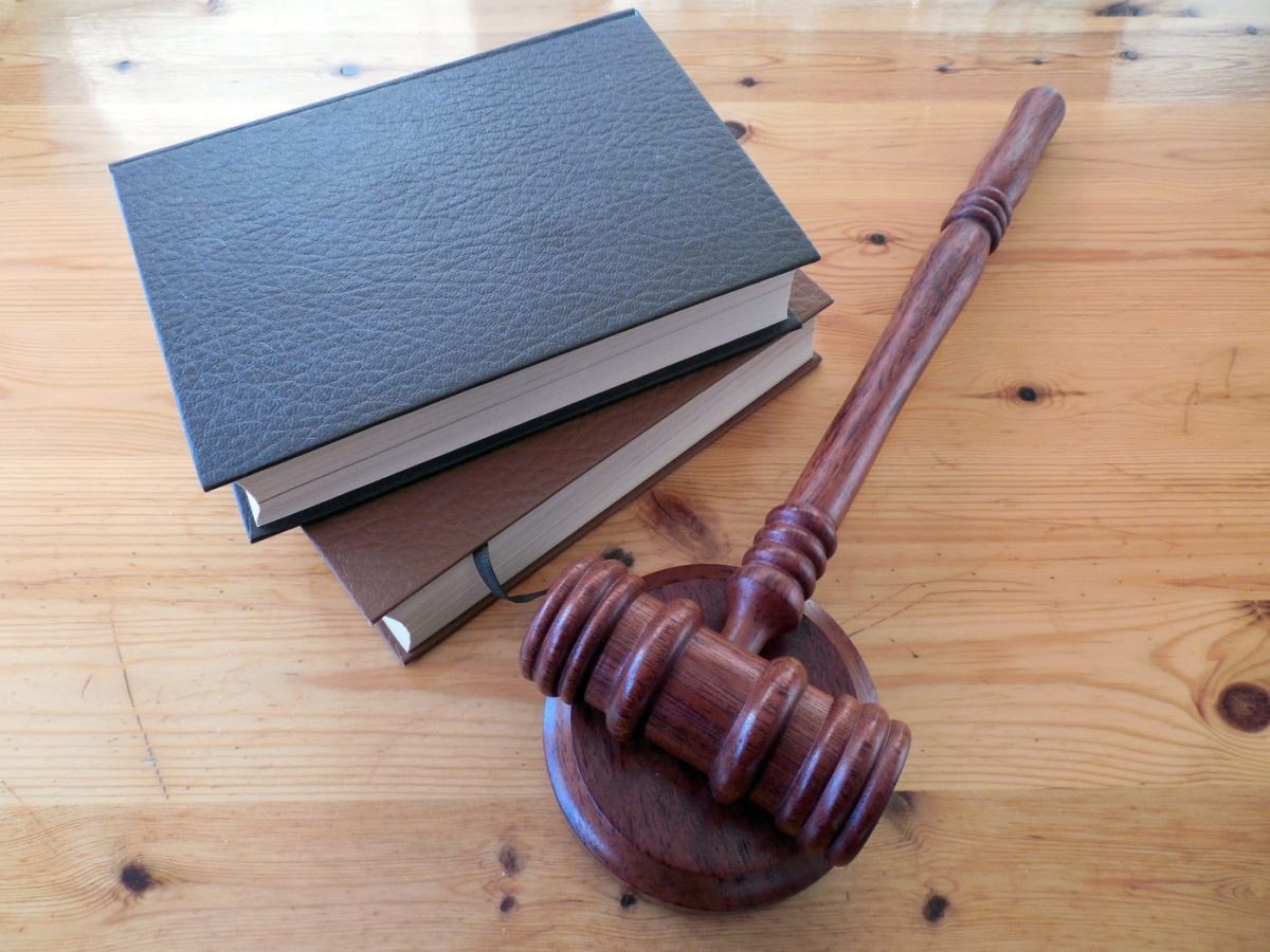 Gavel resting on a stack of three hardbound books on a wooden table, symbolizing law and justice.